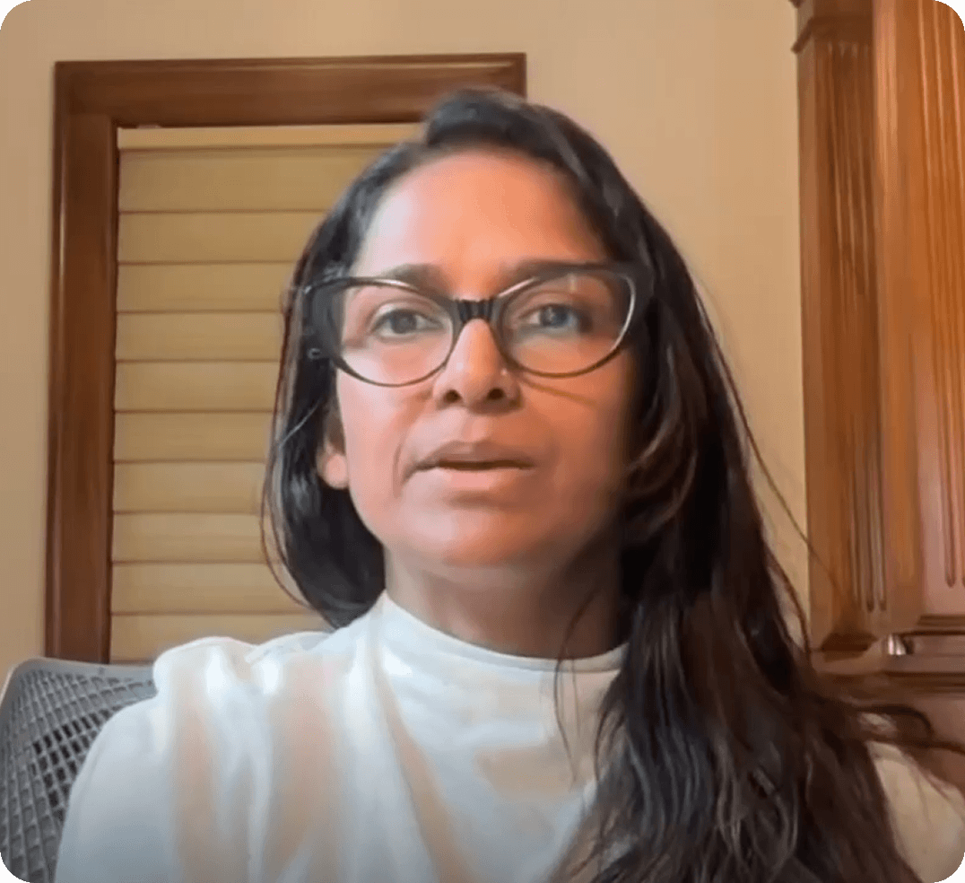 A woman with glasses looking at the camera during a video call.