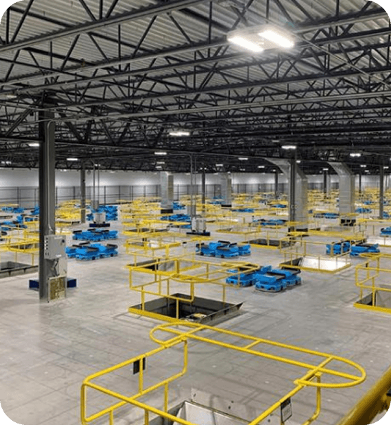 Large industrial warehouse with automated robotic fulfillment systems and yellow safety railings.