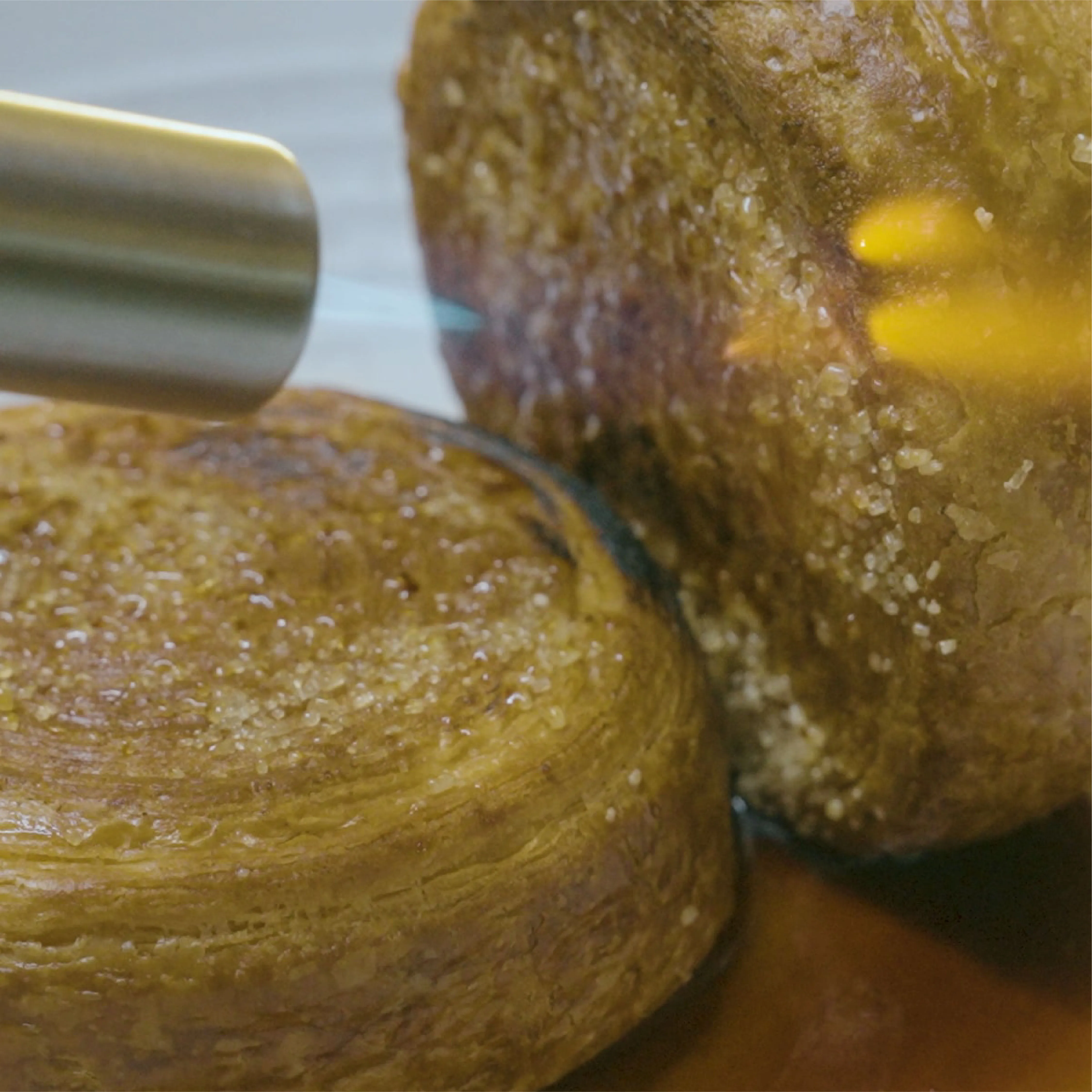 Close-up of a kitchen torch caramelizing sugar on round pastries with a crispy golden crust.