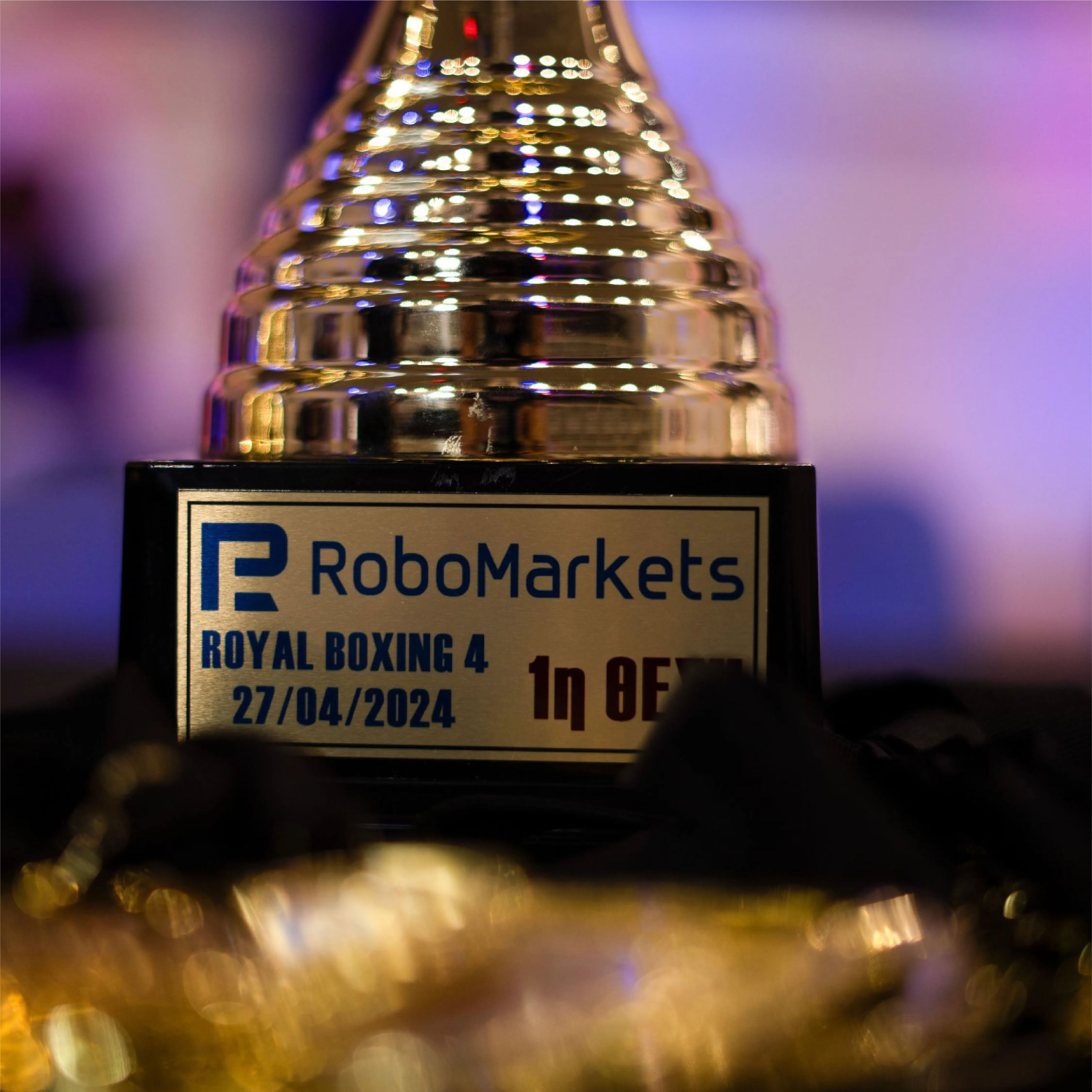 Close-up of a gold trophy with a plaque reading 'RoboMarkets ROYAL BOXING 4 27/04/2024'.