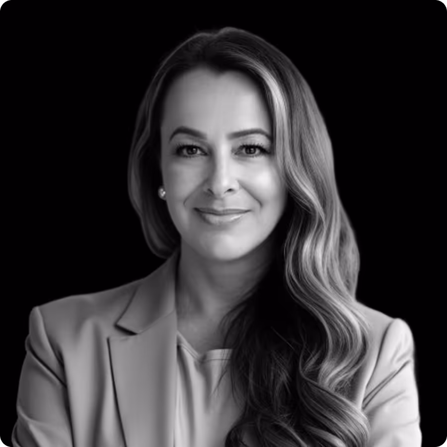 Black and white portrait of a confident woman with long wavy hair wearing a blazer.