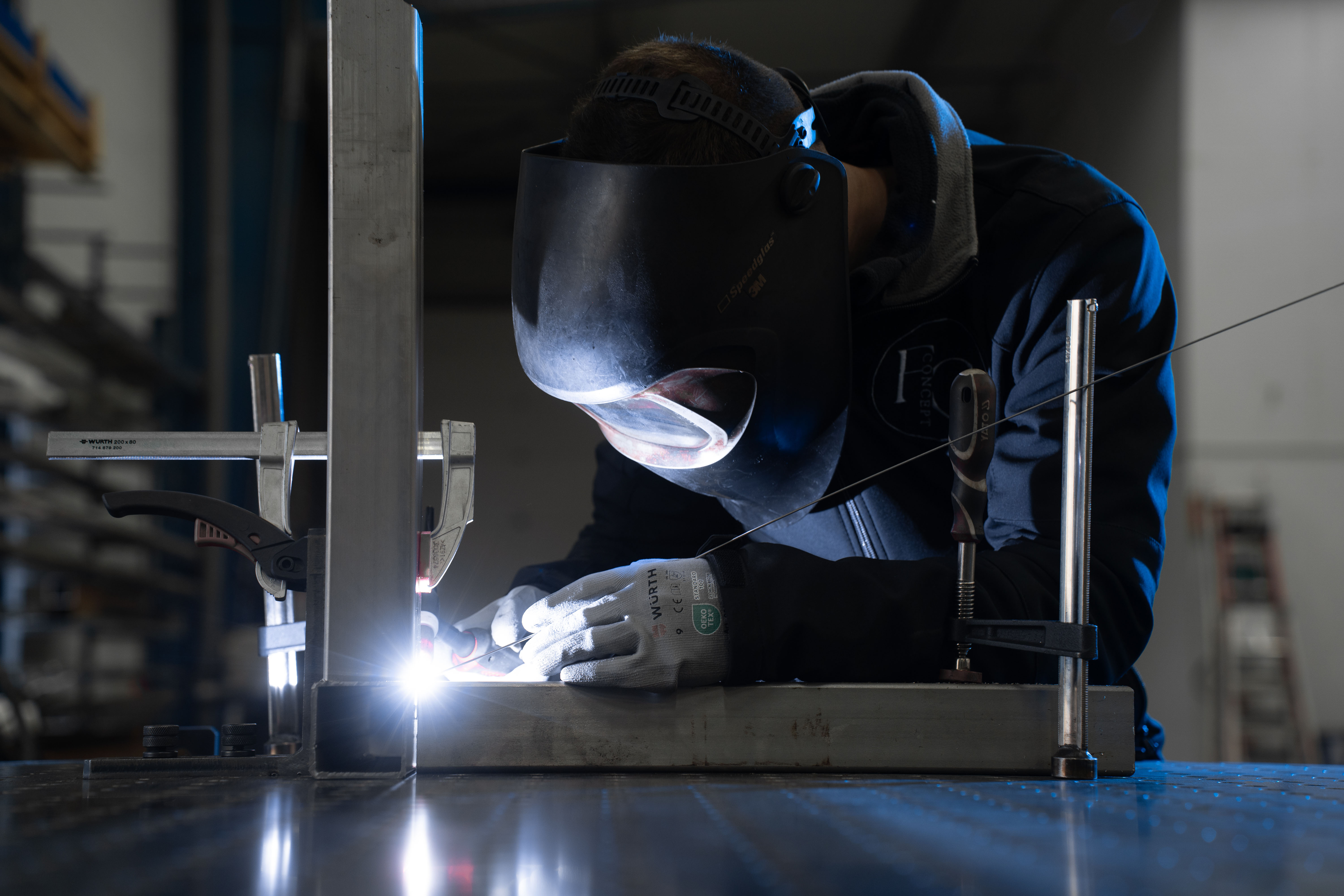Un soudeur réalise une soudure sur son plan de travail
