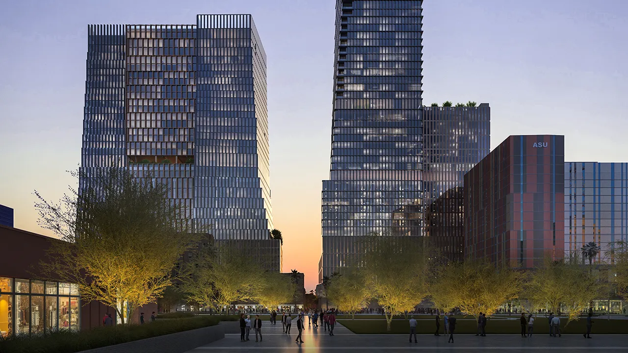 Evening view of a modern city plaza with people walking, trees lit from below, and tall glass buildings.
