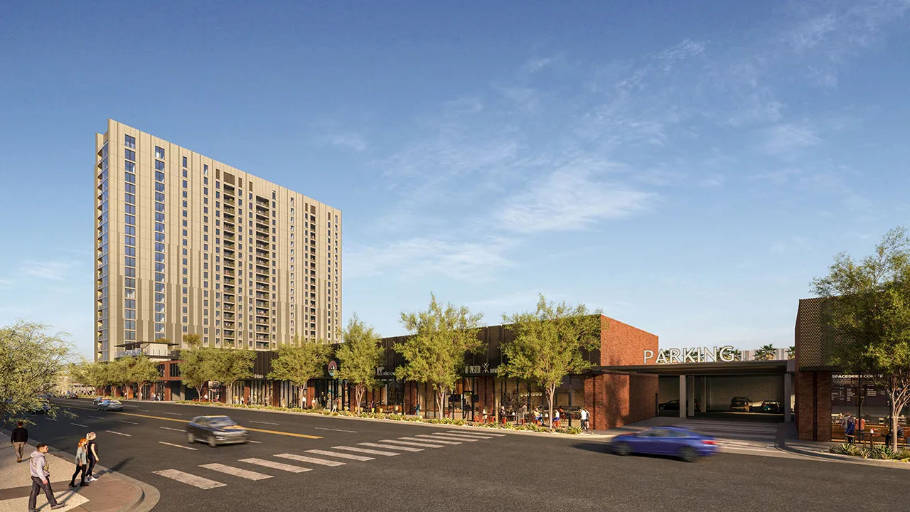Street view of The Whitney, a tall modern building with balconies and ground-level shops at street corner on sunny day.
