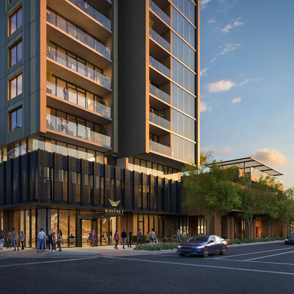 Sunset street view of Whitney high-rise with people walking and cars driving nearby.