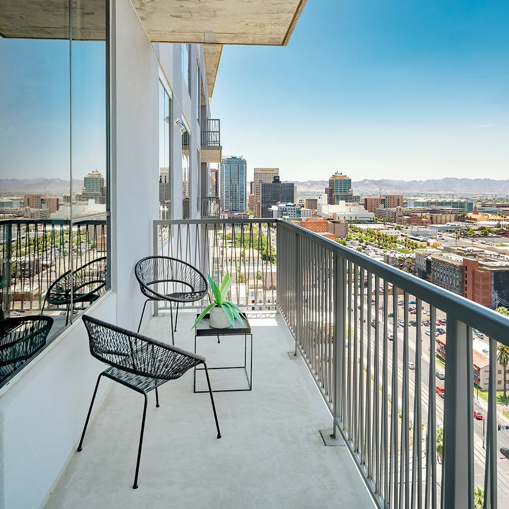 High balcony with two black chairs, table with a plant, overlooking Downtown Phoenix.