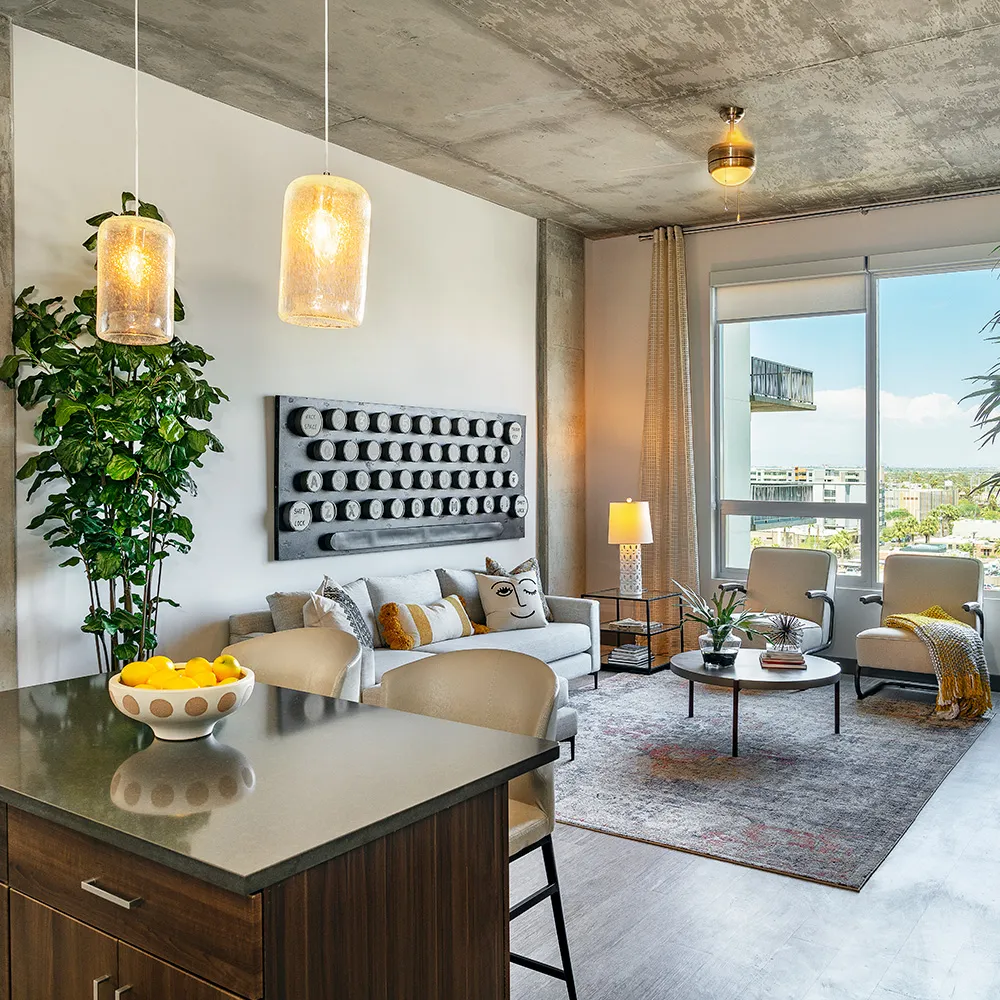 Modern living room with concrete ceiling, gray sofa, two armchairs, dining island, and city view window.