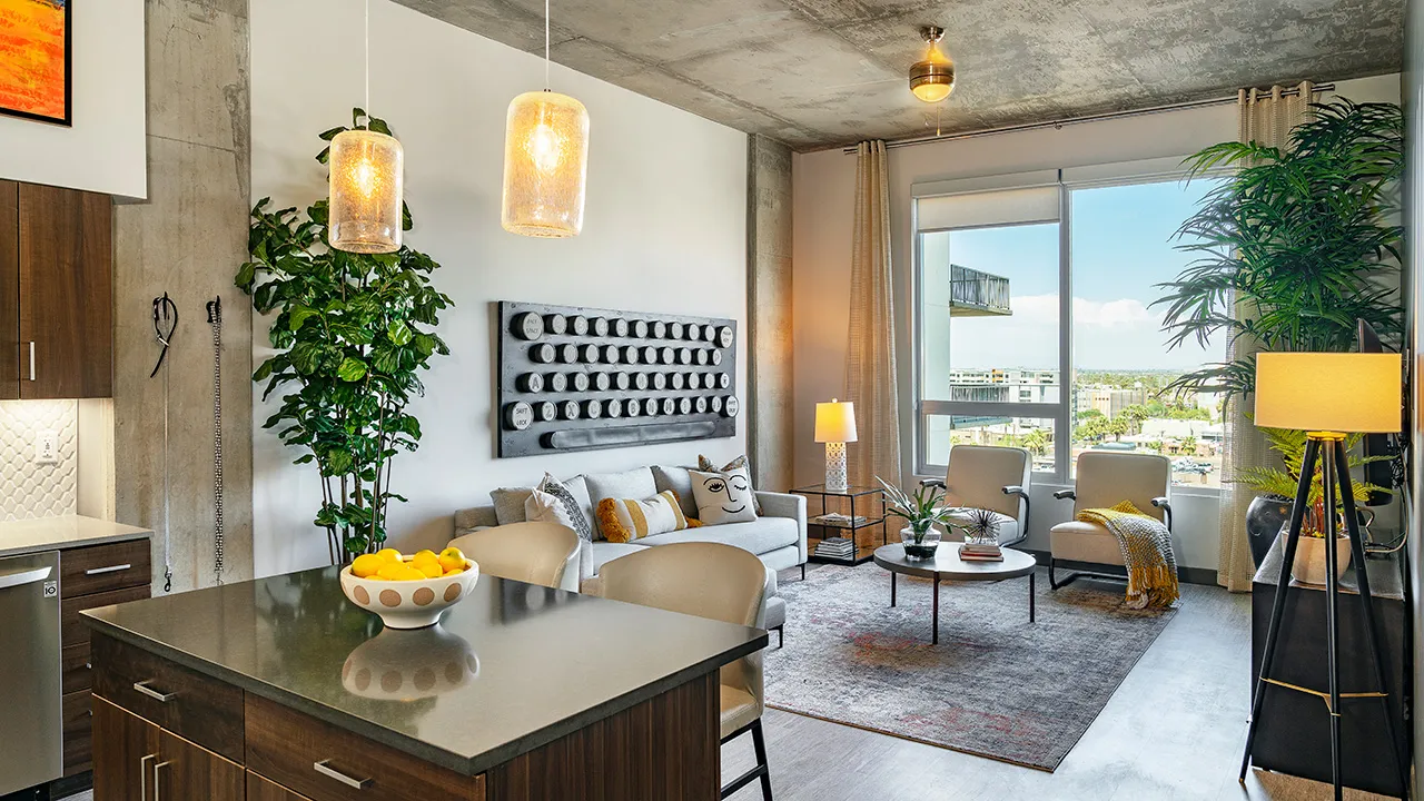 Modern living room with concrete ceiling, gray sofa, two armchairs, dining island, and city view window.