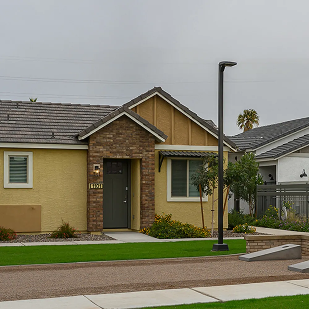 Single-story residential homes with yellow and white exteriors, and green lawns on a cloudy day.