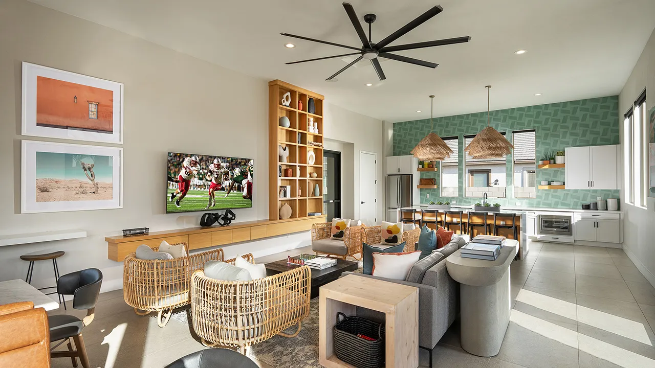 Modern clubhouse seating area with marble tables, wicker chairs, and a stylish kitchen in background.