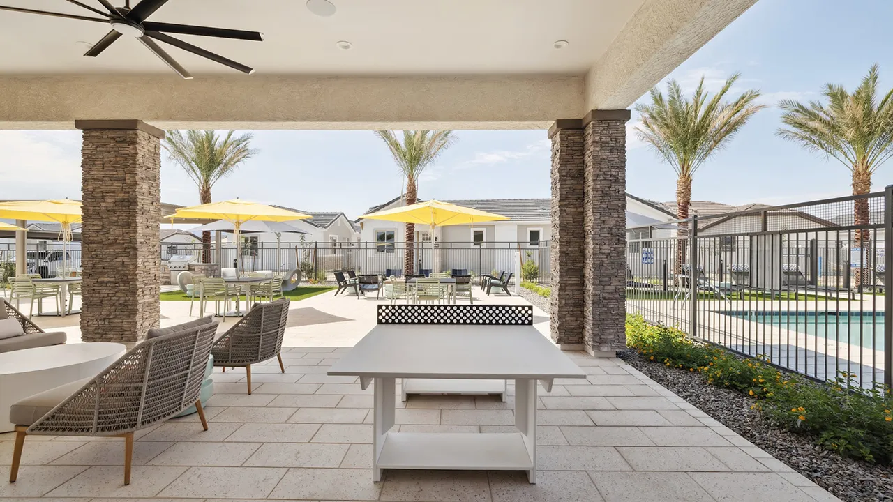 Outdoor patio with stone pillars, lounge chairs, ceiling fans, and ping pong table.