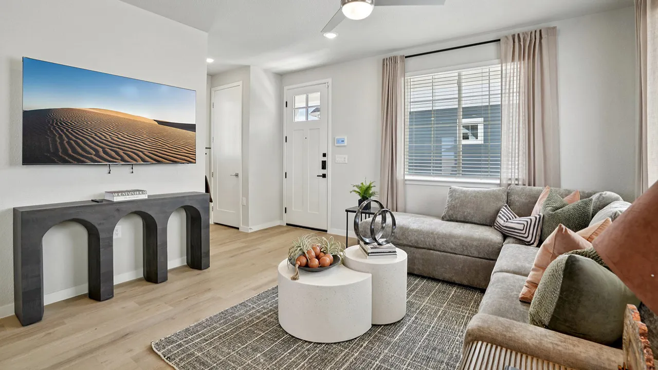 Modern living room with gray sectional sofa, round white coffee tables, and desert dune wall art.