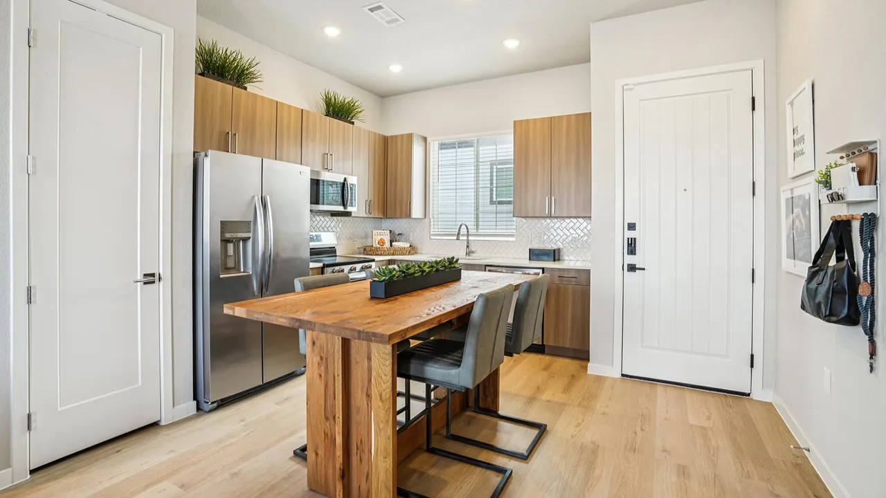 Modern kitchen with wood cabinets, stainless steel appliances, wooden island, and gray chairs.