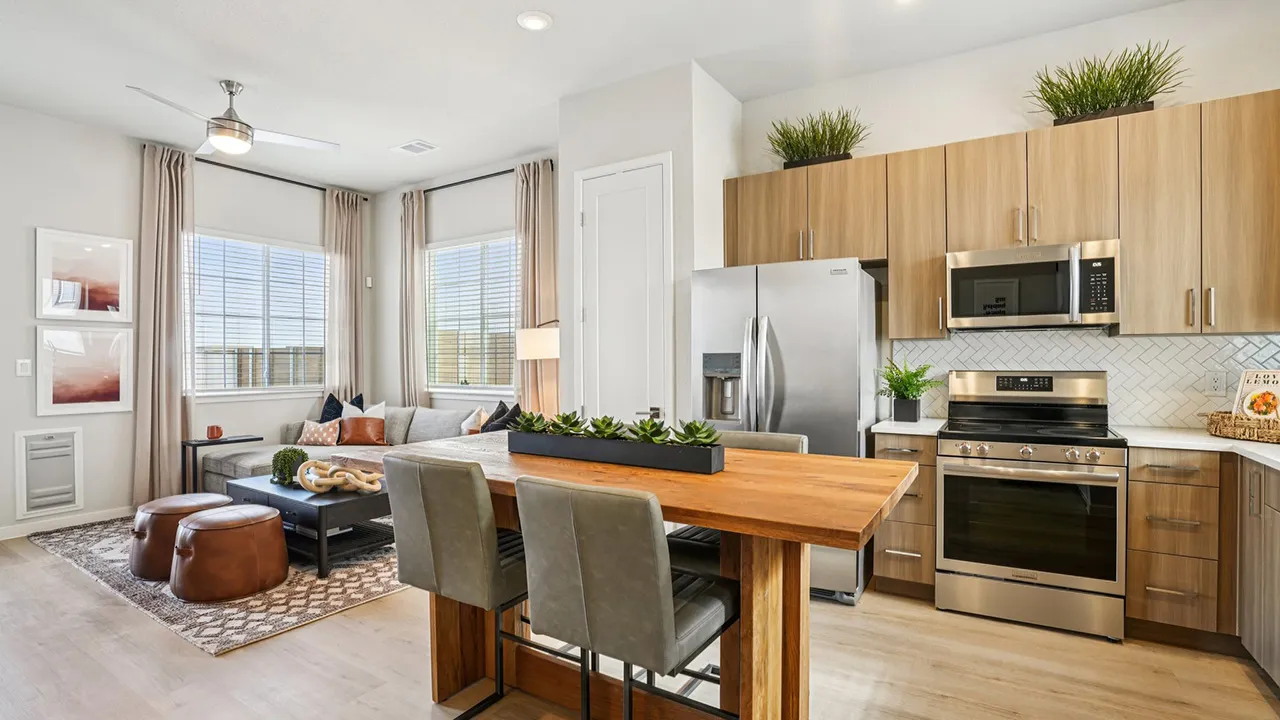 Modern kitchen and living area with wooden cabinets, stainless steel appliances, and a wooden dining table.