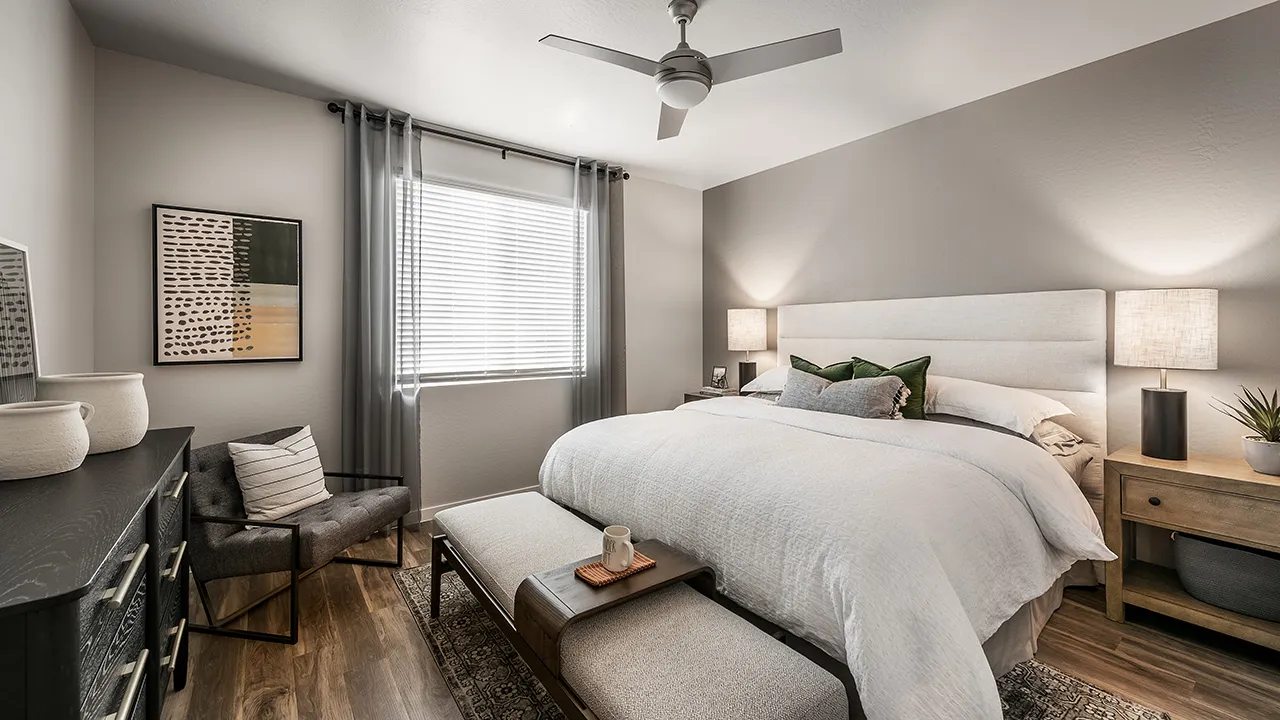 Modern bedroom with a large bed, white bedding, wooden nightstand, chair, dresser, and decorative wall art.