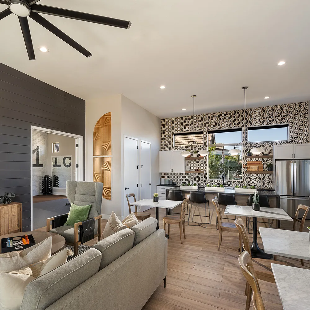 Modern open lounge and kitchen with patterned tile wall, seating area, and marble tables with chairs.