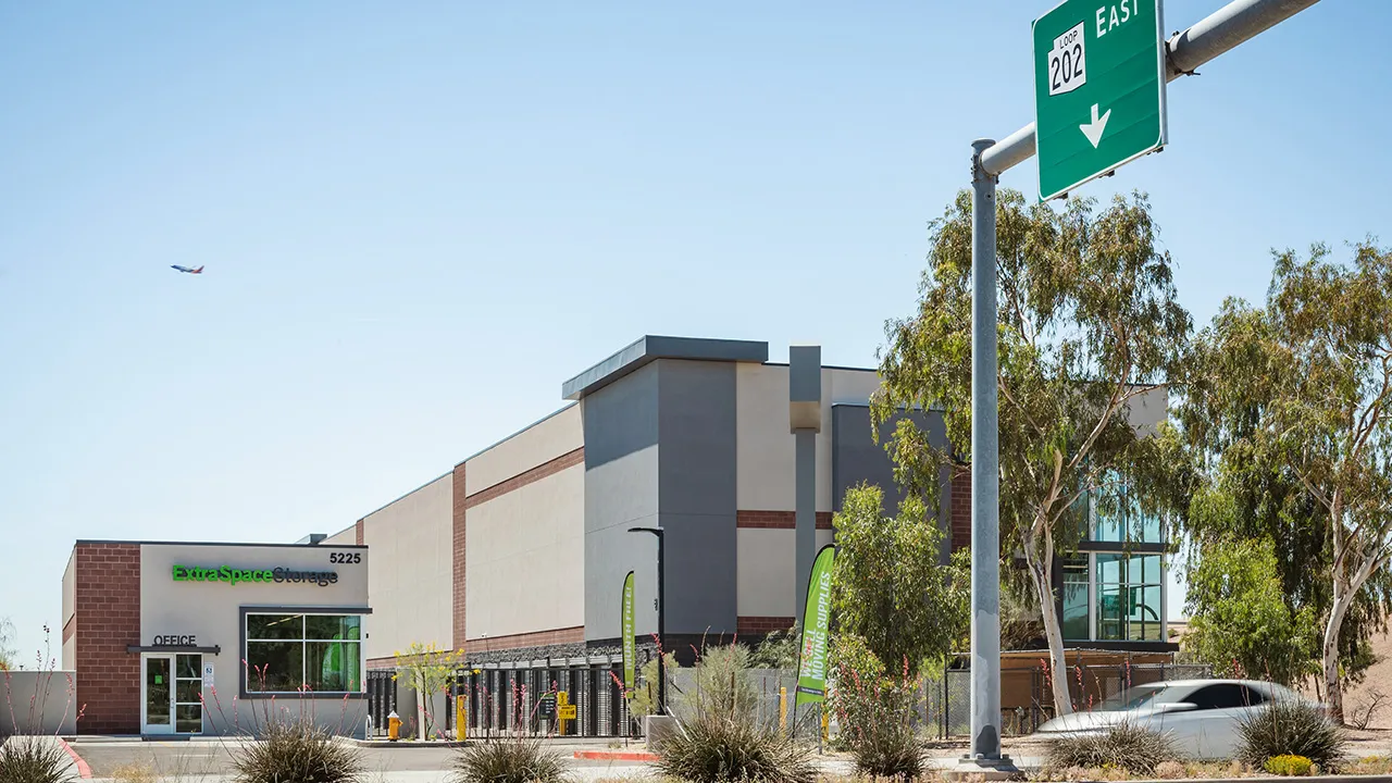The street view of an Extra Space Storage facility next to a freeway entrance road sign reading '202 east'