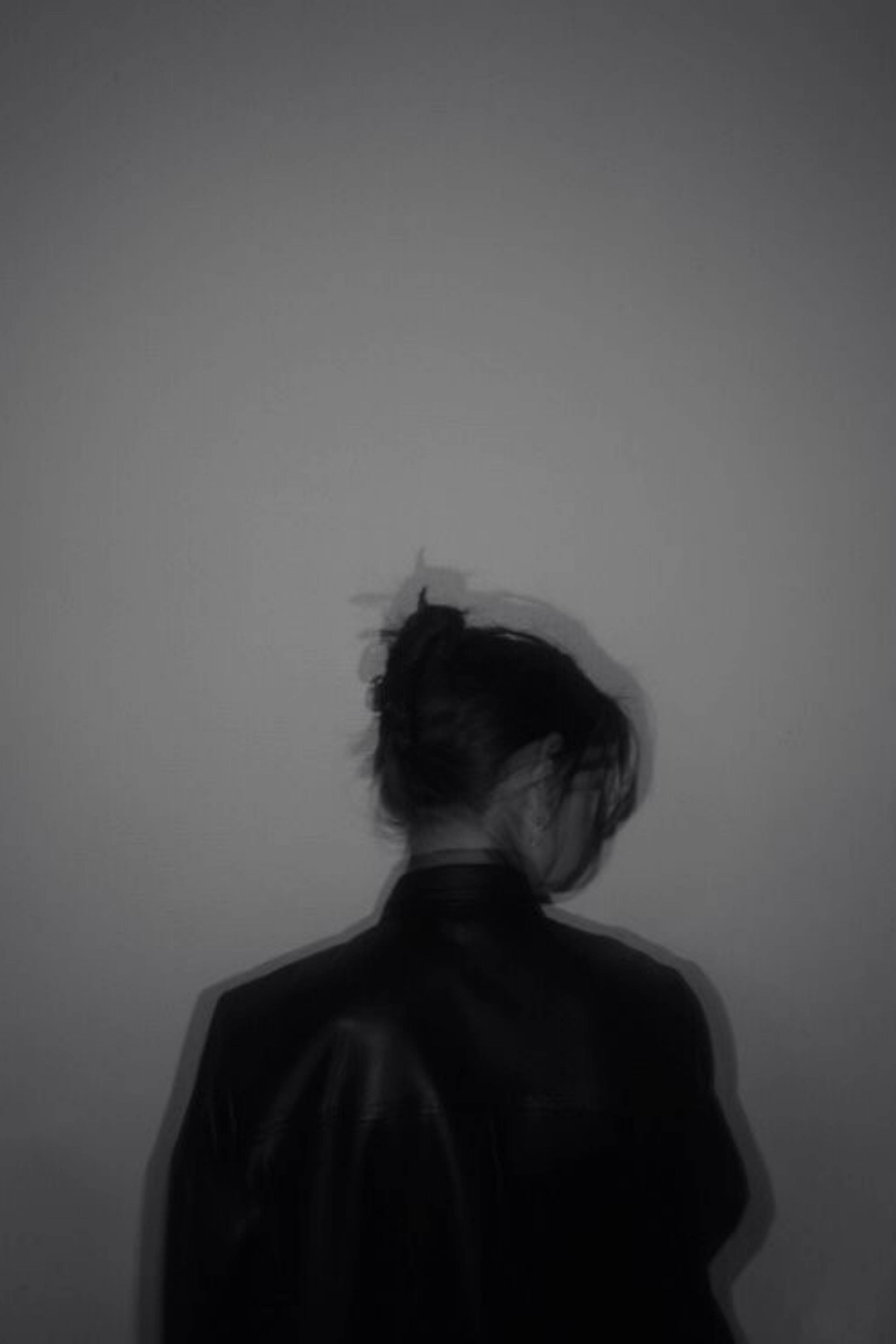 Woman in a floral dress walking through a sunlit field with tall grass and lens flare.