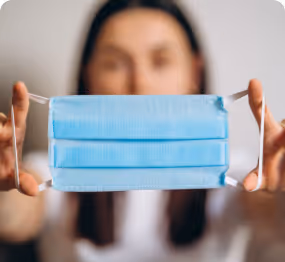 Person holding a blue disposable face mask stretched out in front.