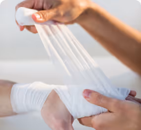 Hands wrapping a white elastic bandage around a wrist.