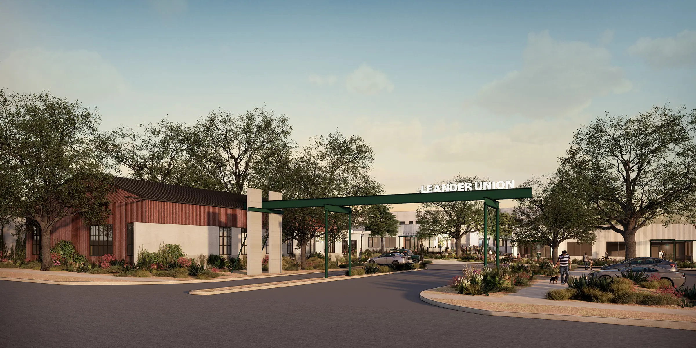 Entrance to Leander Union with green canopy over the road, landscaped sidewalks, trees, and people walking near parked cars.