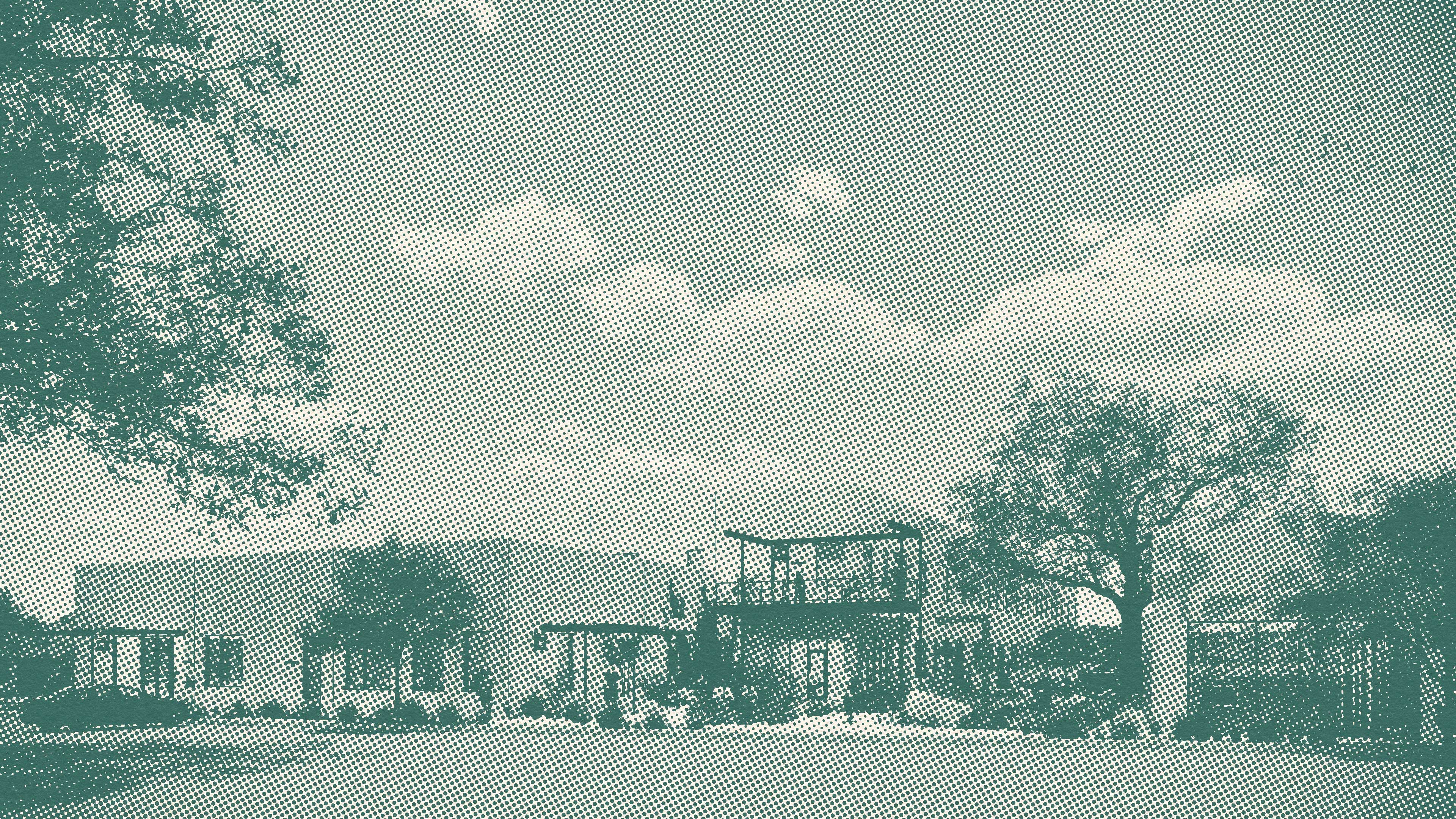 Modern building with flat roof and outdoor seating area surrounded by trees under a partly cloudy sky.