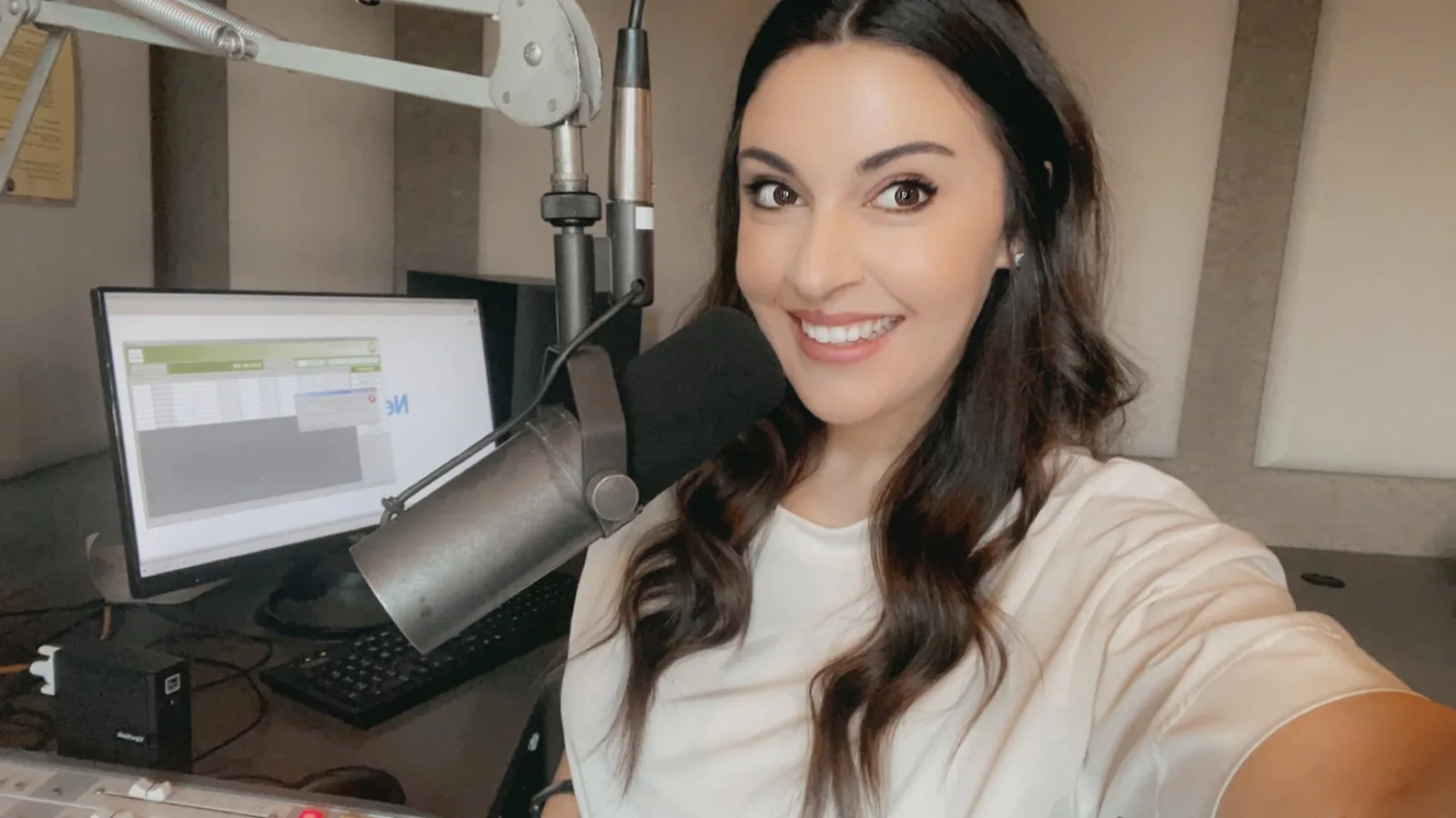 Farren Lange, co-owner of A/F Business Solutions, smiling beside a radio studio microphone