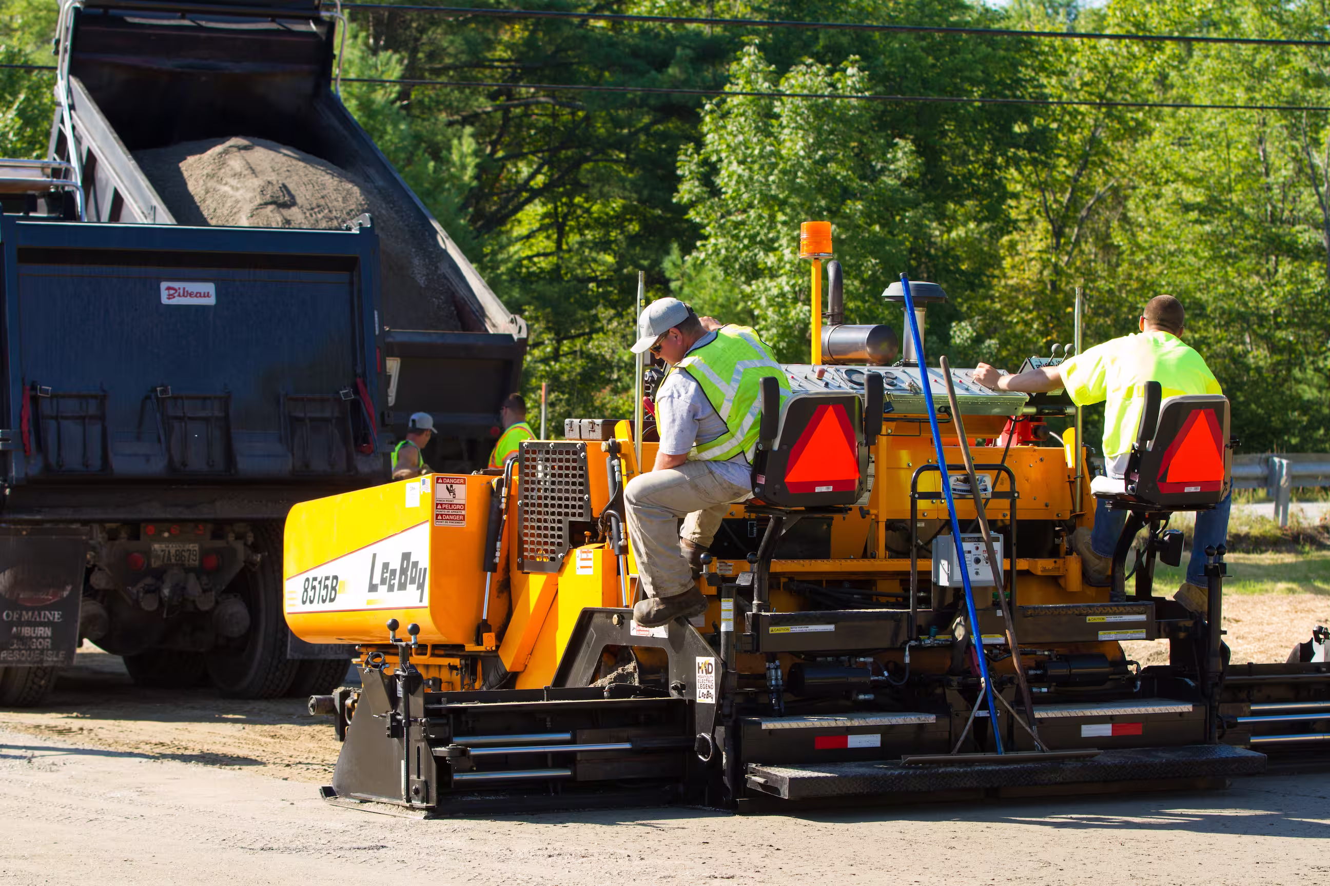 Cooper Paving Worker on a job site with dump truck and paver