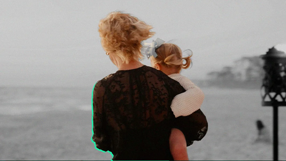 person holding child at beach, viewed from behind