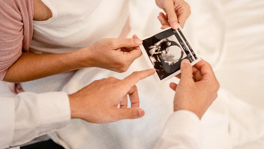 many hands holding a uterine ultrasound