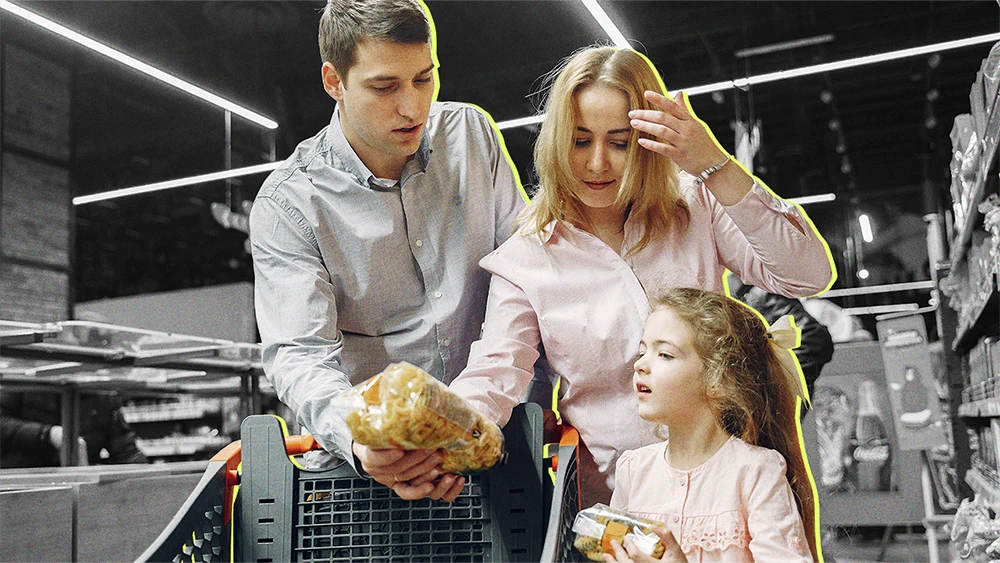 man, woman, and child at a grocery store, looking very concerned about a bag of pasta