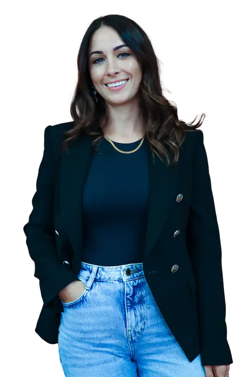 Jessica Chalk: Smiling woman with wavy dark hair wearing a black blazer, black top, gold necklace, and light blue jeans.