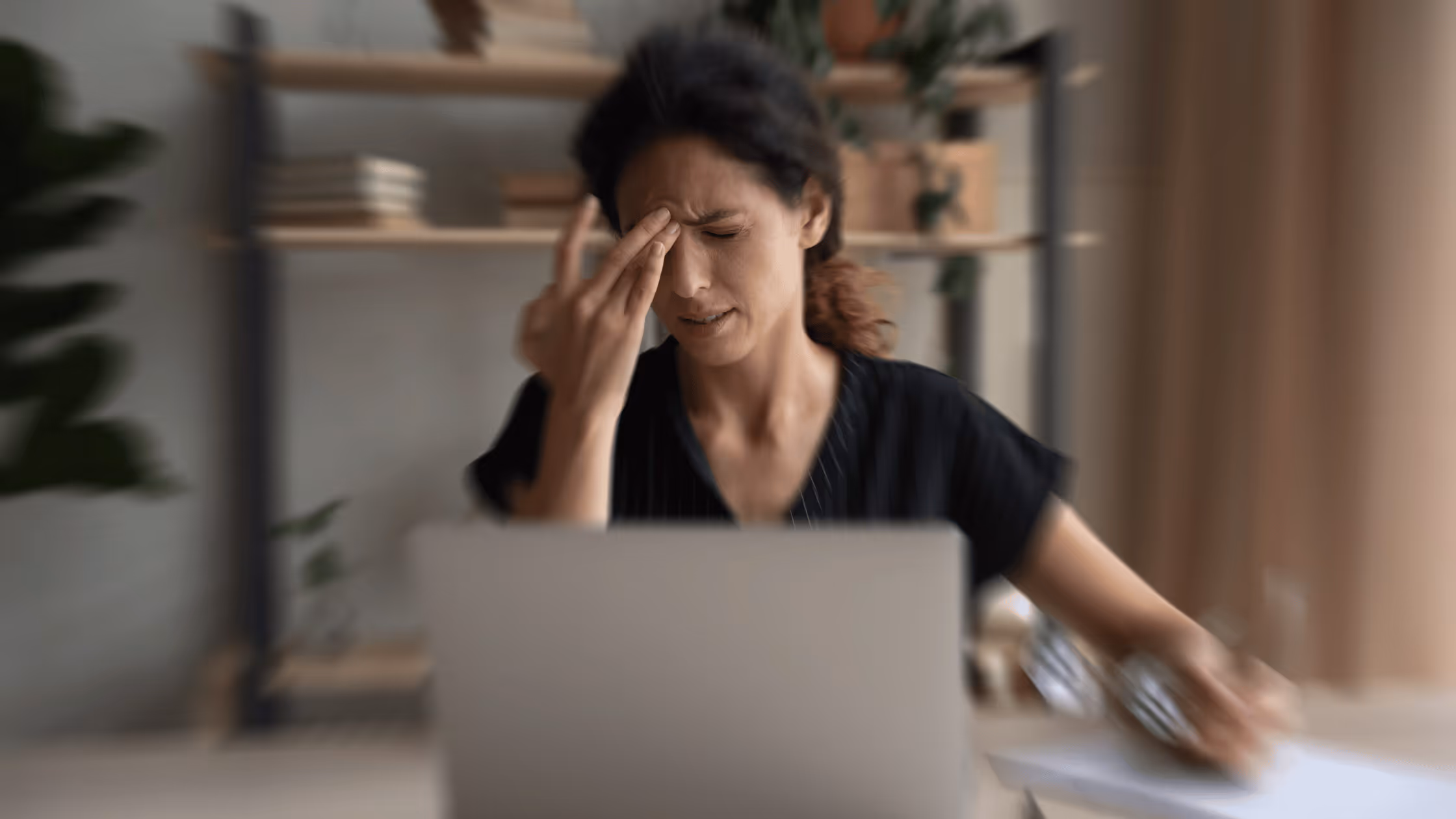 very stressed looking woman on a laptop in a remote workspace