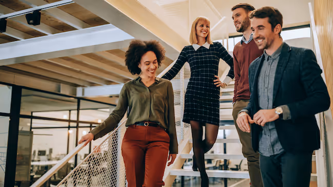 well-dressed employees in a post modern workspace, walking down the stairs looking content