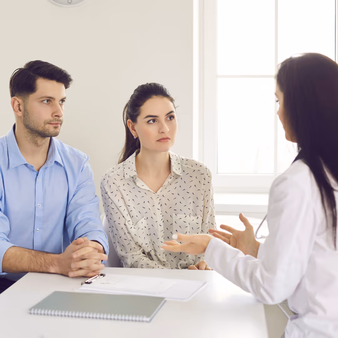 engaged woman and nervous man sit across from a doctor at a fertility consultation