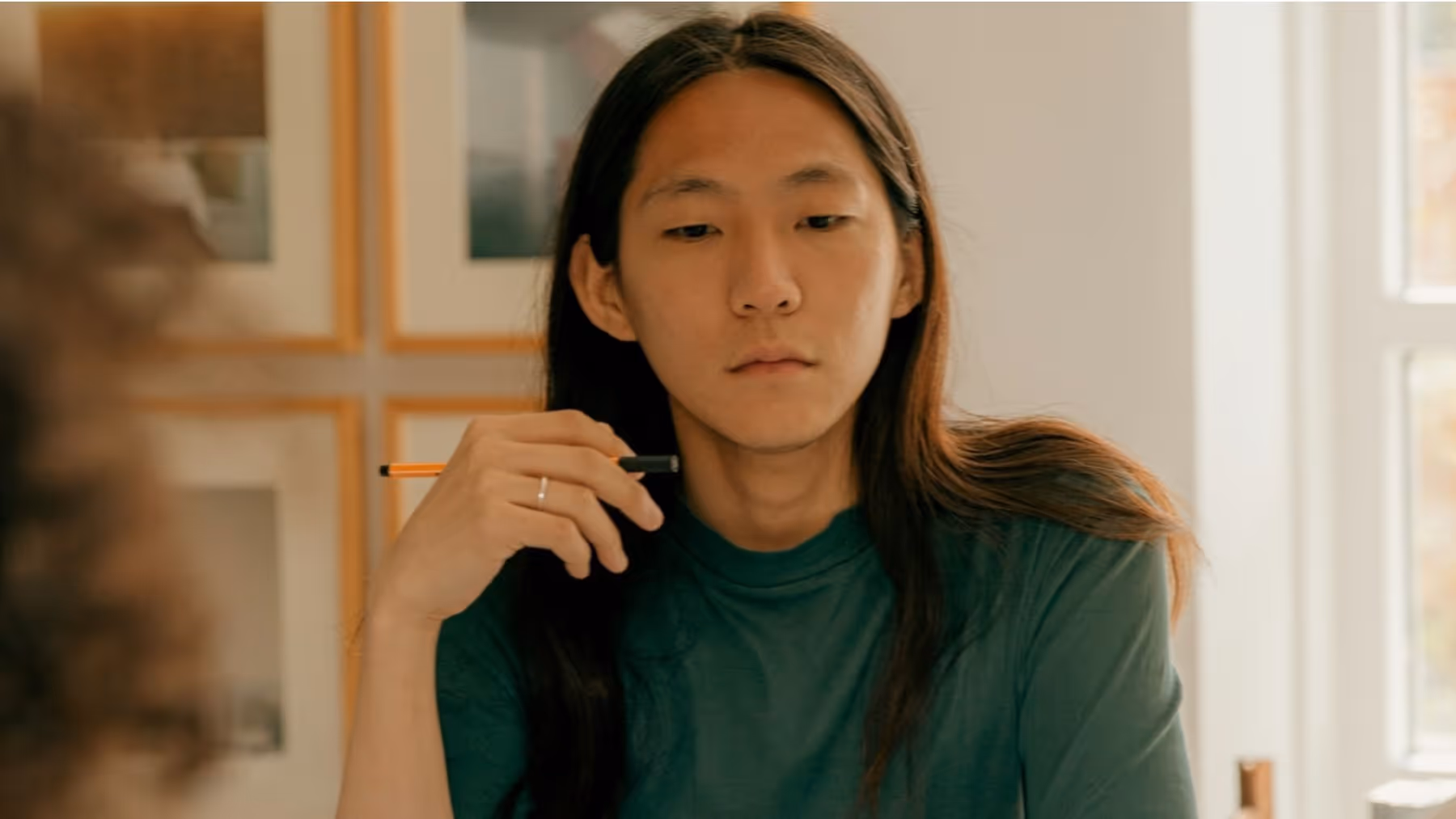 pensive person in late 20s or early 30s, holding a pen