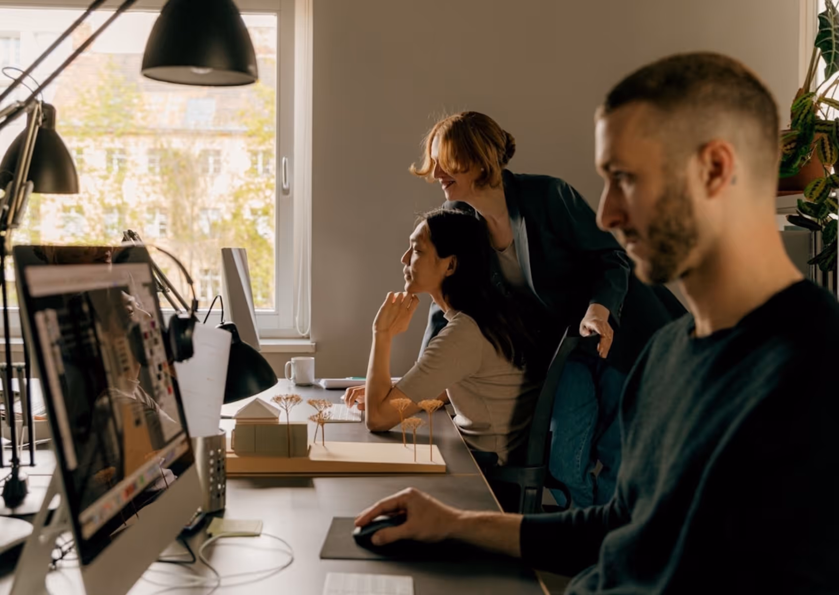 man and woman at separate iMac computers, being overseen by a smiling support woman