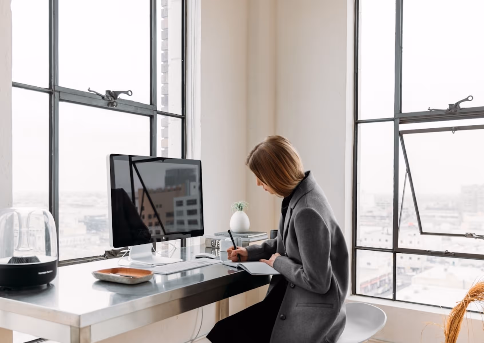 studious woman at a computer writing in a notebook from an elevated luxury loft condominium