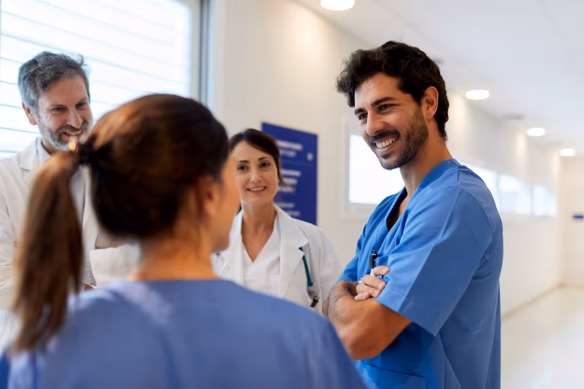 a group of healthcare professionals have a conversation in a hallway.