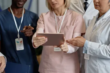 three healthcare professionals look at a view of information on a tablet