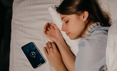 Woman sleeping beside an active smartphone