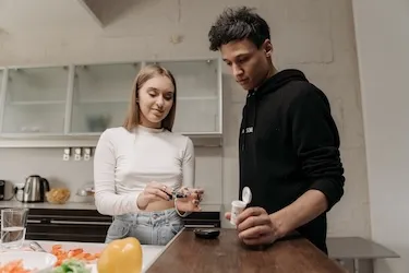 two youths prepare dinner while testing blood sugars