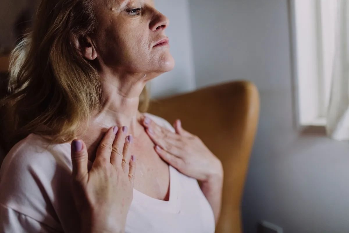 a woman cooling her upper chest while touching her collarbones