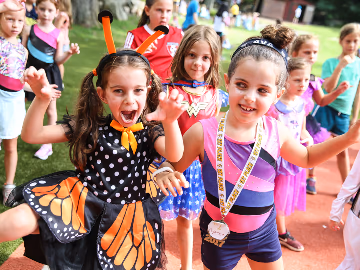 Group of young girls wearing costumes and playing outdoors on a playground.