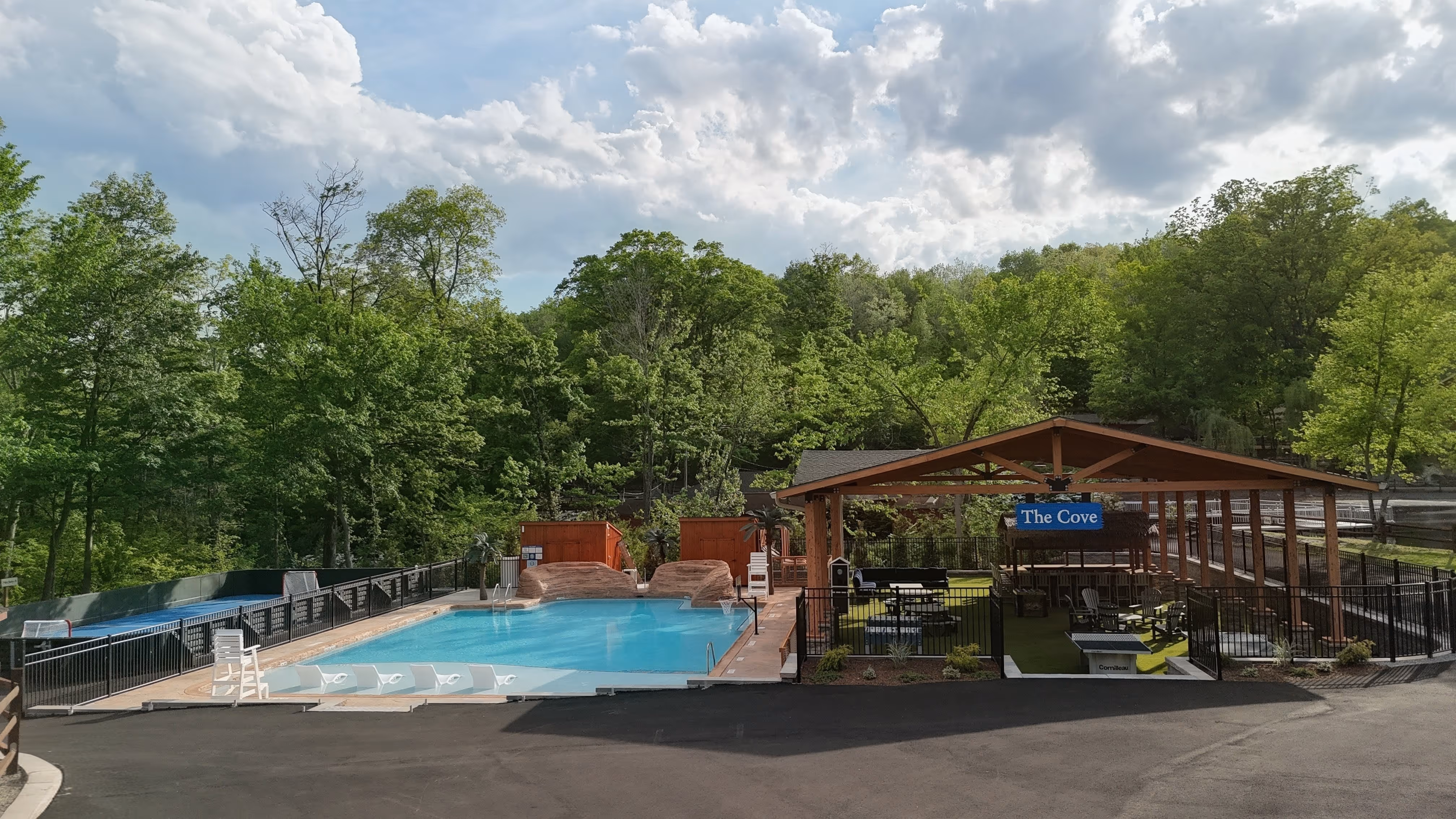 Outdoor pool area with lounge chairs, a covered seating area labeled The Cove, and surrounding trees.