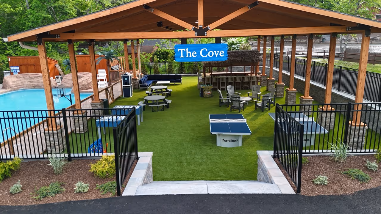 Outdoor covered lounge area with picnic tables, Adirondack chairs, ping pong tables, and a bar named The Cove.