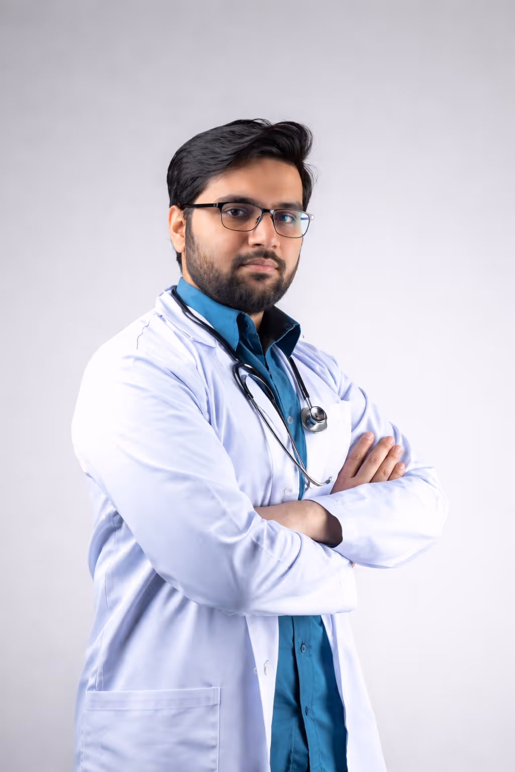 Confident doctor with glasses and stethoscope standing with arms crossed against a plain background.