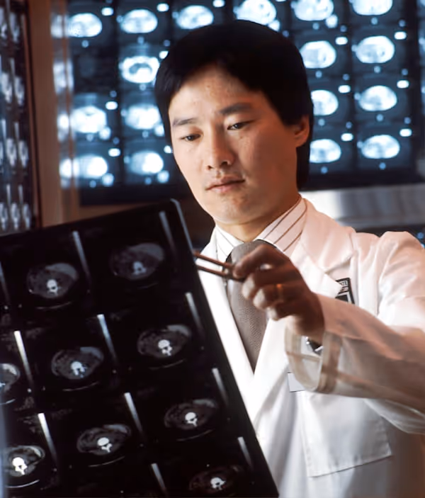 Close-up of a healthcare professional in a white coat holding a stethoscope toward the camera.