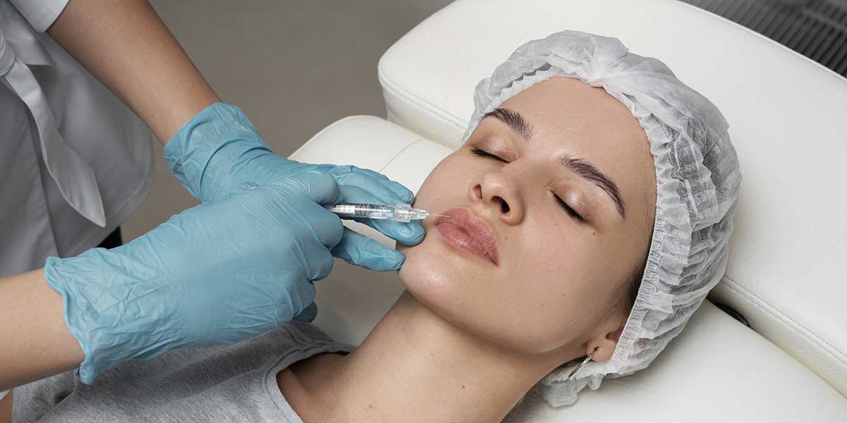 A medical professional gives lip filler injections to a woman near Cortland, OH to enhance volume and natural contour.