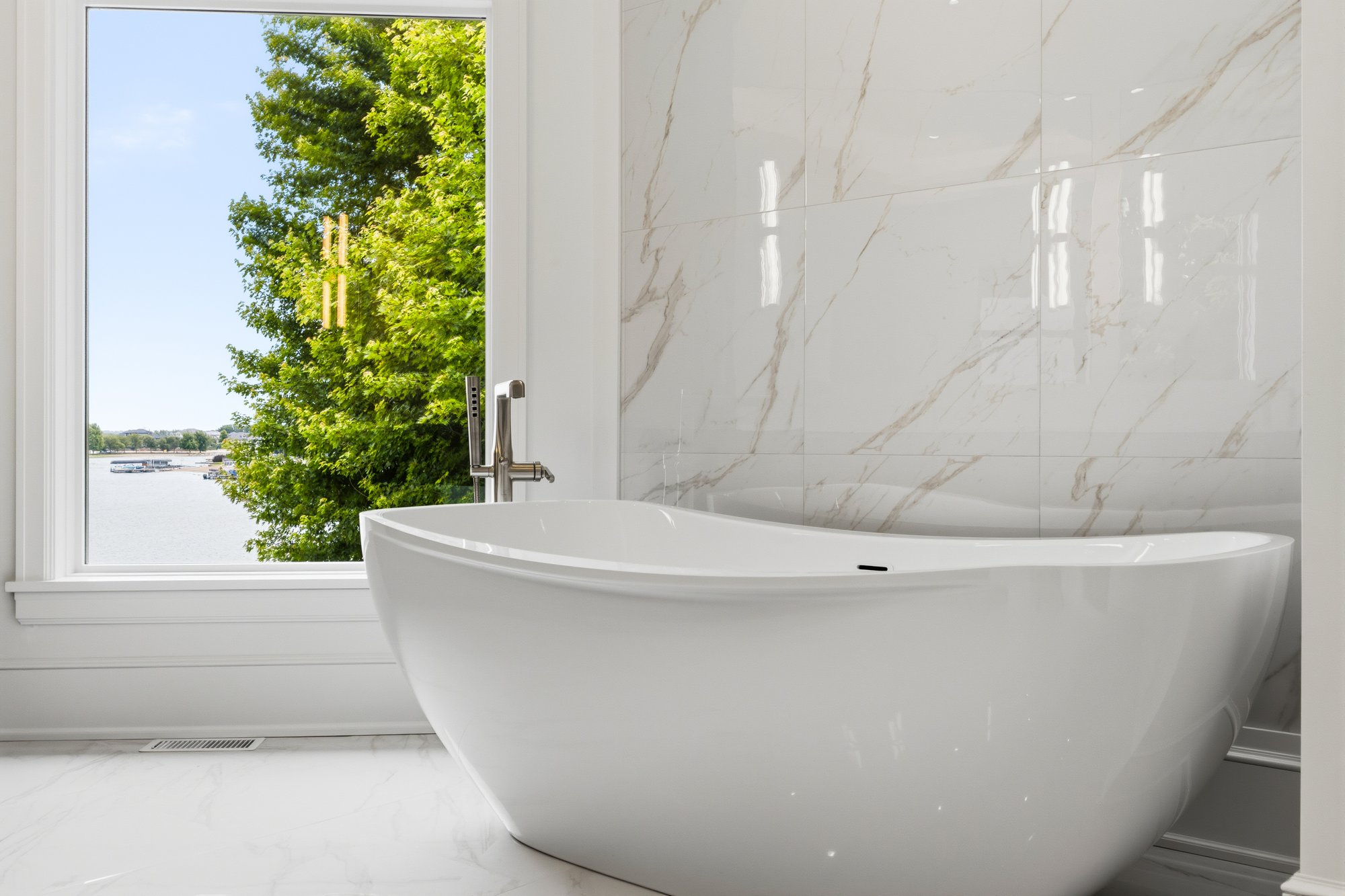 Freestanding tub with marble wall and lake view